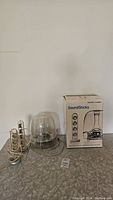 Harman Kardon subwoofer, two SoundSticks satellite speakers, and the original SoundSticks packaging box placed on a surface.