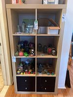 Front view of IKEA shelving unit showing six cubbies with various items (excluded) and four black drawers at bottom.
