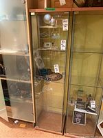 Shelving unit shown in storage area, depicts complete shelving unit with glass door closed and contents removed.