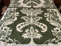 Full view of wool jacquard blanket spread over a queen size bed showing green background with cream foliage motifs.