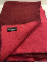 Blanket folded showing both sides, rich burgundy and dark muted coral colors with label visible