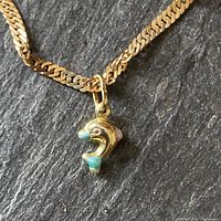 Close-up of dolphin charm suspended on chain on slate background