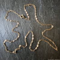 Full chain laid flat on dark slate surface showing oval link pattern