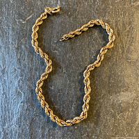 Full view of twisted rope chain bracelet laid on dark background