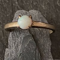 Front view of ring showing round opal in four-prong setting on gold band