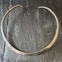 Top view of the slightly curved heavy solid sterling silver band choker with open ends showing the smooth hammered texture and hand shaped form.