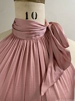 Close-up view of the gathered neckline and tie detail on the side of the muted coral blouse