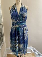 Front view of blue, turquoise, and cream gathered dress displayed on mannequin.