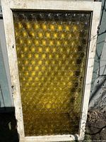 Full view of amber glass door in weathered wooden frame leaning against exterior wall