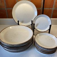 Overview of entire set showing stacks of large dinner plates and smaller dessert plates on a white surface against tiled background.