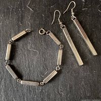 Bracelet and earrings set displayed flat on dark surface showing design and size