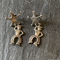 Front view of both cowboy earrings showing the sheriff star badges and cowboy figures dangling below.
