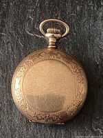 Front of round gold filled pocket watch case with engraved border.
