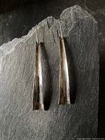 Front view of both silver drop earrings showing their elongated tapered shape and hammered texture.