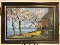 Framed painting showing lakeside scene with cottages, trees, and red canoe.
