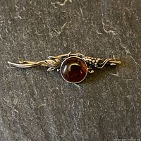 Front view of vintage sterling silver pin showing grape cluster design and amber cabochon.