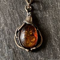 Close-up of the oval amber cabochon pendant with winding silver cord setting.