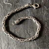 Full view of the vintage sterling silver rope chain bracelet resting on a dark stone surface showing its length and clasp.