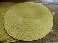 Close-up of one yellow oval woven placemat showing textured circular weaving and color.