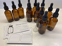 Photo showing the 12 amber glass essential oil bottles with dropper lids, funnel, and sticker sheets arranged on a white surface.
