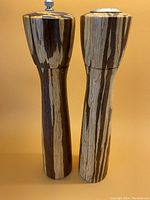 Front view of pepper grinder and salt shaker, showing dark and light striped wood grain finish.