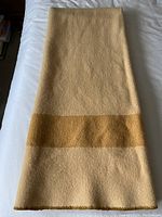 Full view of folded blanket showing cream field and mustard stripe at center.