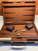 Complete view of the opened backgammon case showing playing surface, dice cups, playing pieces, dice and doubling cube.