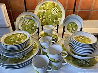 Full array of plates, bowls, cups and saucers arranged on countertop against tiled backsplash