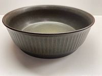 Front angle view of the avocado green casserole dish showing shallow depth and textured ridged exterior.