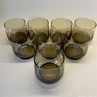 Front view of all 8 smoky brown lowball glasses arranged in a group.