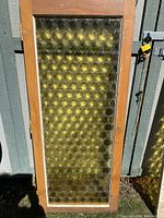 Full view of the rectangular amber textured glass window framed in wood, showing the window size and overall condition.