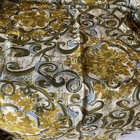 Close-up photo of the vintage fabric laid flat, showing the detailed mid-century modern pattern primarily in shades of mustard yellow, olive green and cinnamon brown with blue highlights.