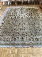 Full view of the rectangular wool carpet laid flat on wood parquet floor, showing the overall design and colors.