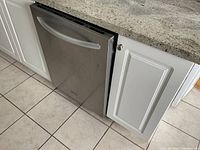 Front view of stainless steel dishwasher installed under countertop