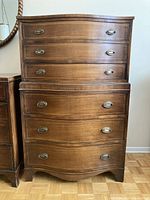 Front view of wooden high boy dresser showing six drawers and metal oval handles.
