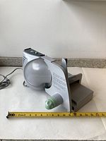 Side view of Krupps electric meat slicer showing blade, adjustment knob, and power cord with measurement for scale.