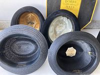 Four vintage men's hats shown from above, detailing interior linings and labels including the 'Biltmore' and 'Knox' brands.