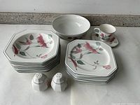 Set of Mikasa floral dinnerware plates, bowl, cup and salt and pepper shakers arranged on a countertop.