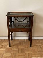 Front view of vintage wooden night table showing glass top shelf, single drawer with metal pull, and lower glass shelf.