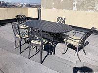 Outdoor dining set featuring an oval table and five chairs arranged on a rooftop patio, showing overall condition and style.