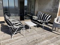 Photo showing the outdoor furniture set with 2 chairs, loveseat, and table on a wooden deck with sliding glass door in background.