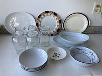 Photo showing 2 large oval serving dishes, 1 large round white serving dish, 2 decorative plates, 4 clear glass jars with lids, 1 small floral ceramic bowl, and 4 plain white small bowls.
