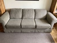 Front view of three-cushion beige fabric sofa with rounded arms.