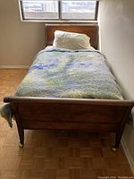 Full view of the vintage twin size bed with blanket and pillow, showing footboard and headboard