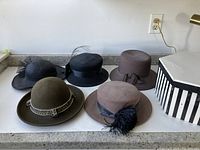 Five vintage women's hats displayed on a countertop showing various styles and details