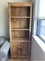 Front view of the wooden bookcase showing two open shelves and closed cabinet doors below.