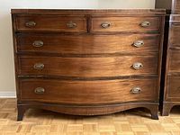 Front view of the wood dresser showing curved front and brass handles.