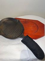 Photo showing close-up of cast iron grill skillet handle cover and wooden serving tray beneath skillet