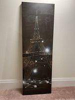 Front view of tall vertical canvas featuring the Eiffel Tower at night with lights and reflections, mounted frameless on a wall.