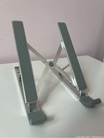 Front view of foldable metallic laptop stand with grey rubber grips on resting bars.